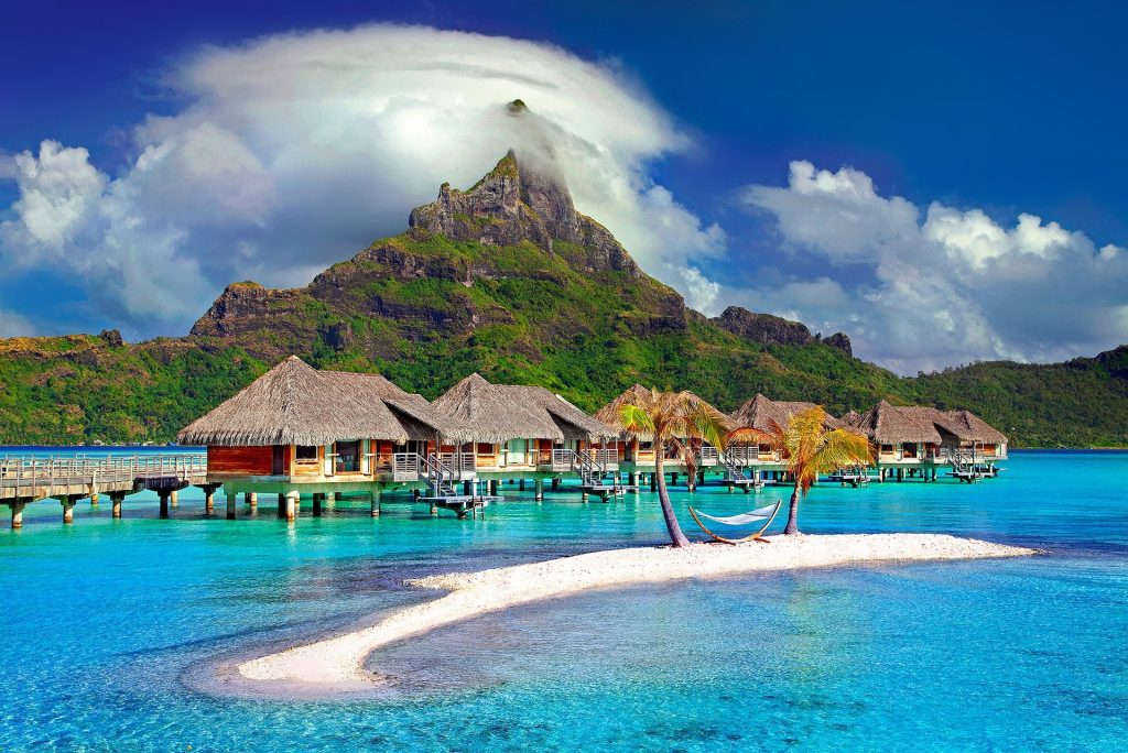 A tropical beach with palm trees and clear blue water.