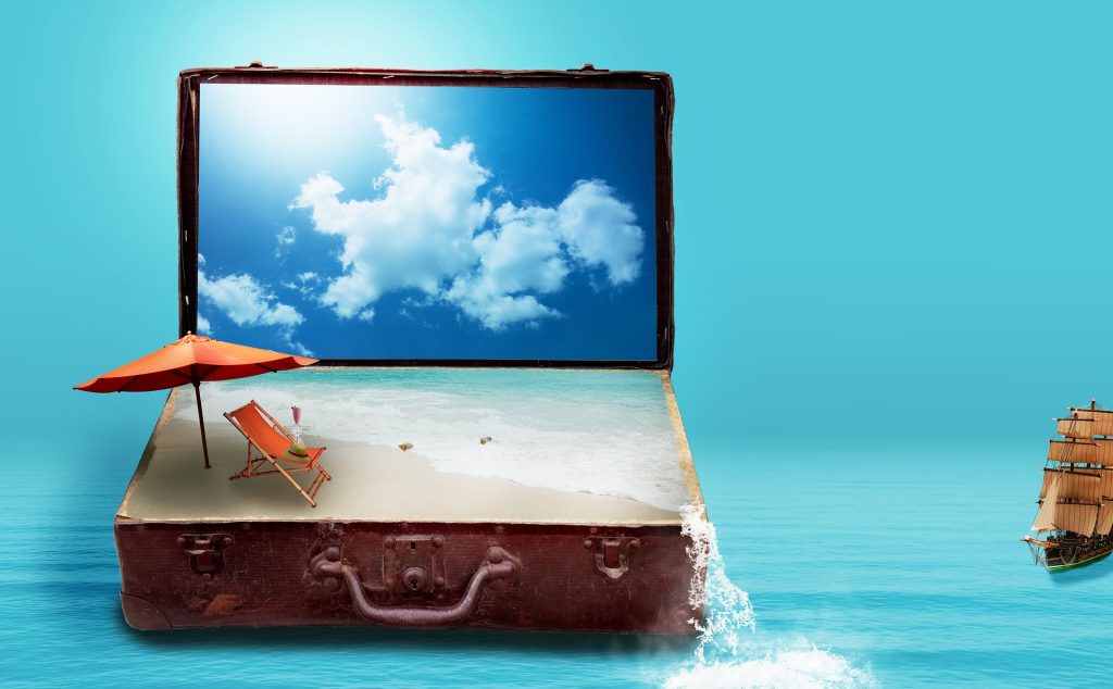 A suitcase with sand and a sailboat in the ocean.