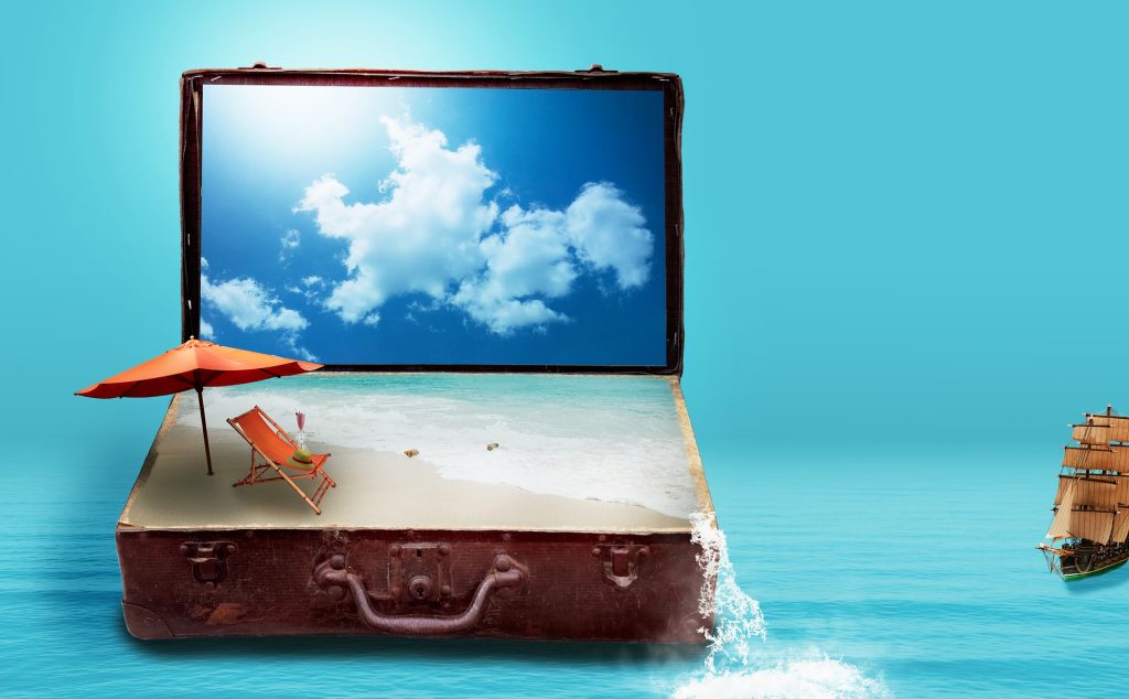 An open suitcase, the bottom half containing a beach scene, with a computer monitor behind showing an image of blue sky.