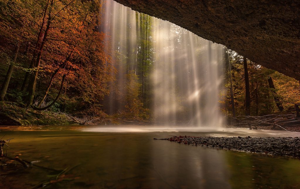 A waterfall seen from behind, surrounded by trees.