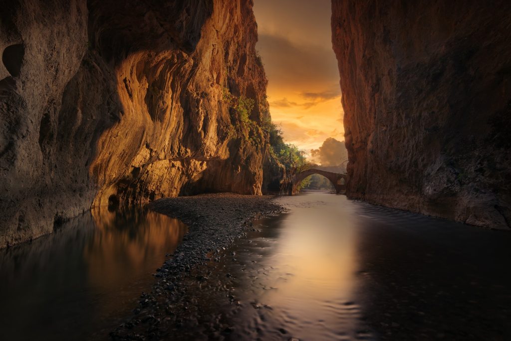 A river is flowing through a canyon at sunset.