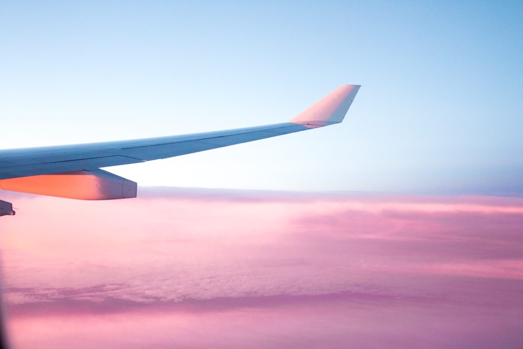 An airplane wing in the sky at sunset.