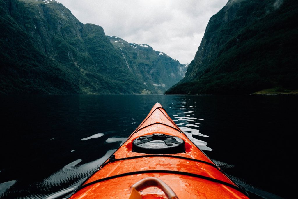 A kayak in the middle of a lake with mountains in the background.