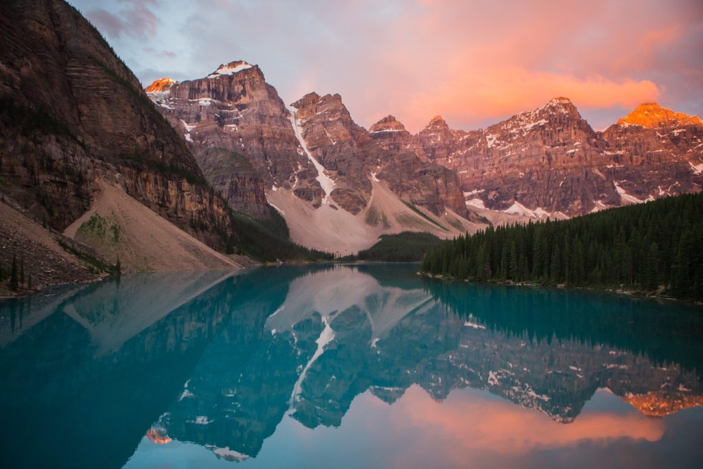 The mountains are reflected in a lake at sunset.
