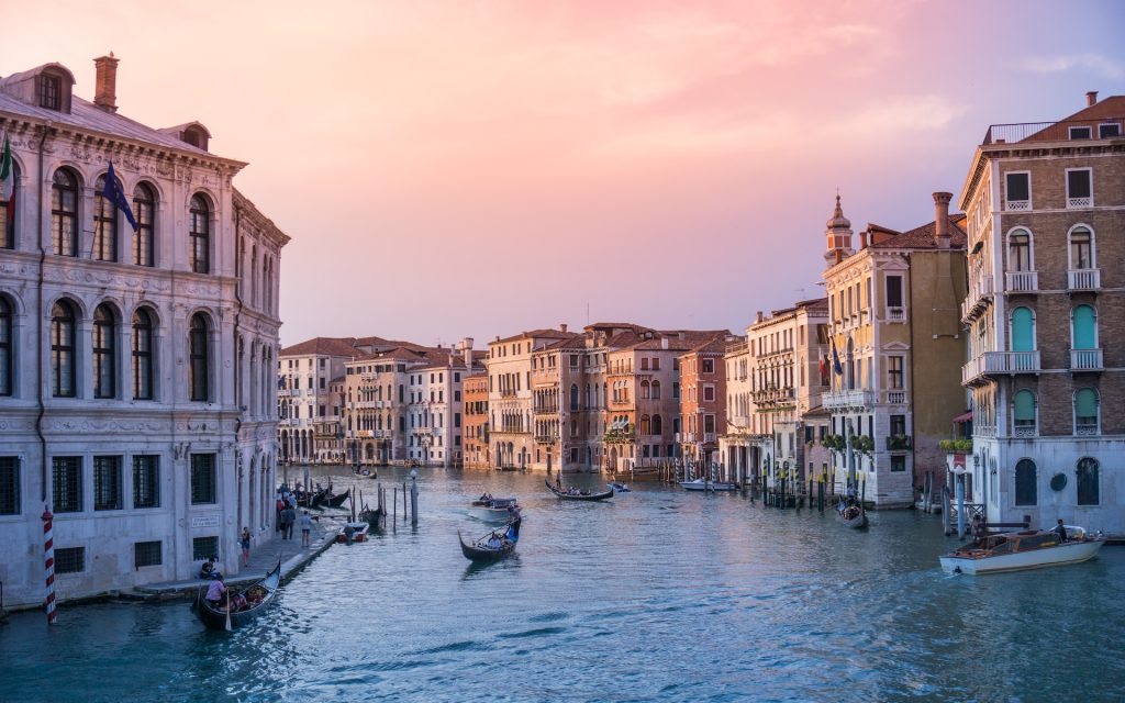 A quiet canal in venice turns gently to the left, surrounded by clssical mid-rise buildings.