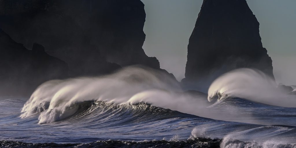Ocean waves rolling and crashing towards the shore, seen from the side.