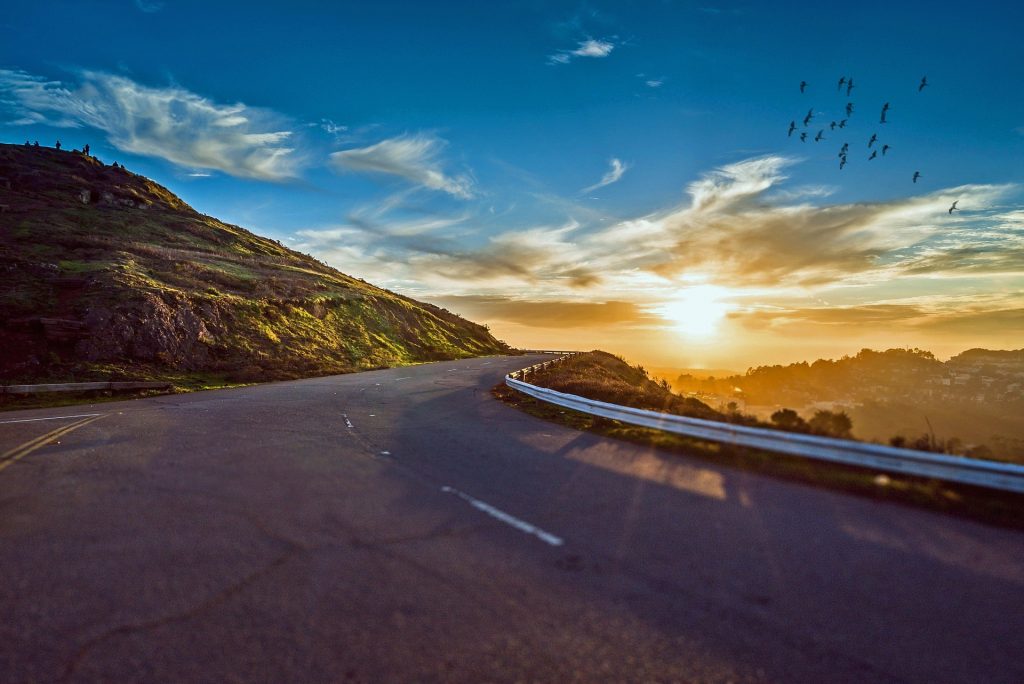 A winding road through a mountainous landscape at sunset.