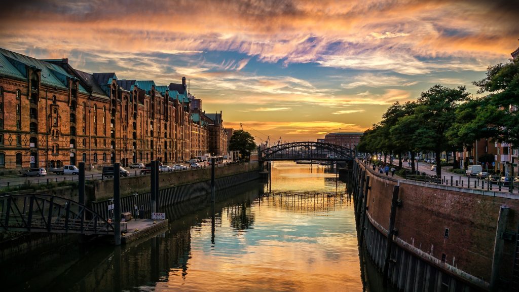 The skyline of Hamburg at dusk with illuminated buildings.