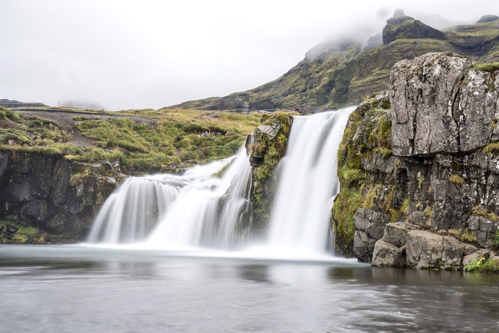 A scenic view of two waterfalls flowing into the same lake.