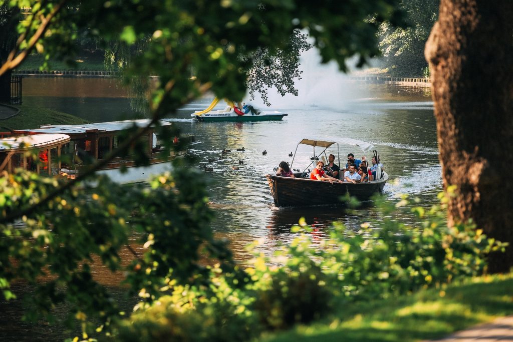 A tranquil river flowing through a lush green landscape, and a boat sailing by.