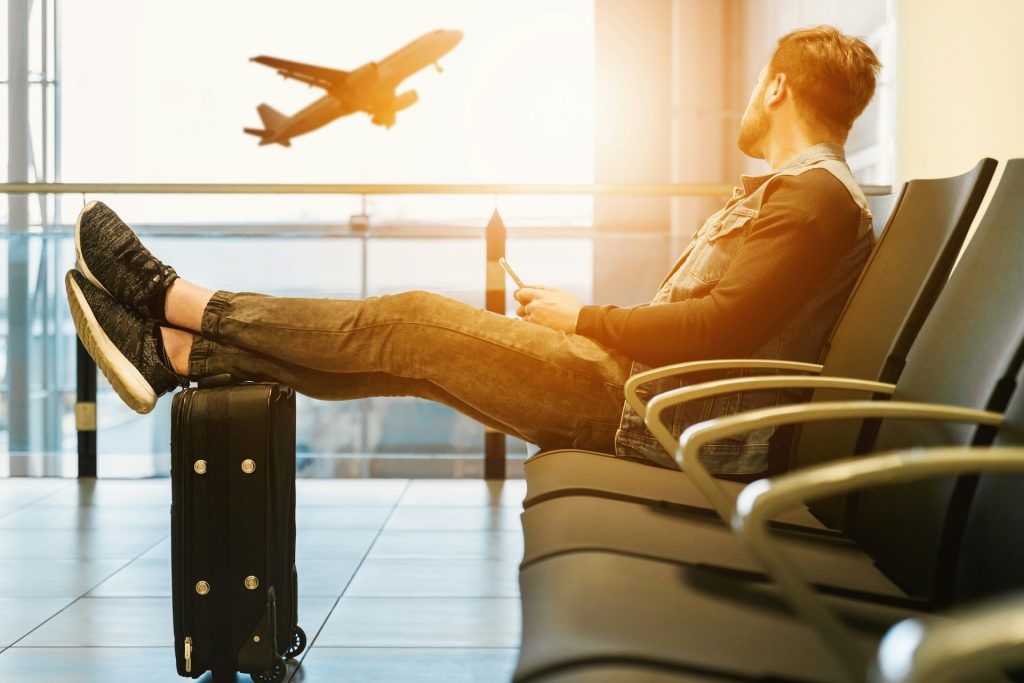 A man relaxing in a departure lounge, feet up on his travel case.