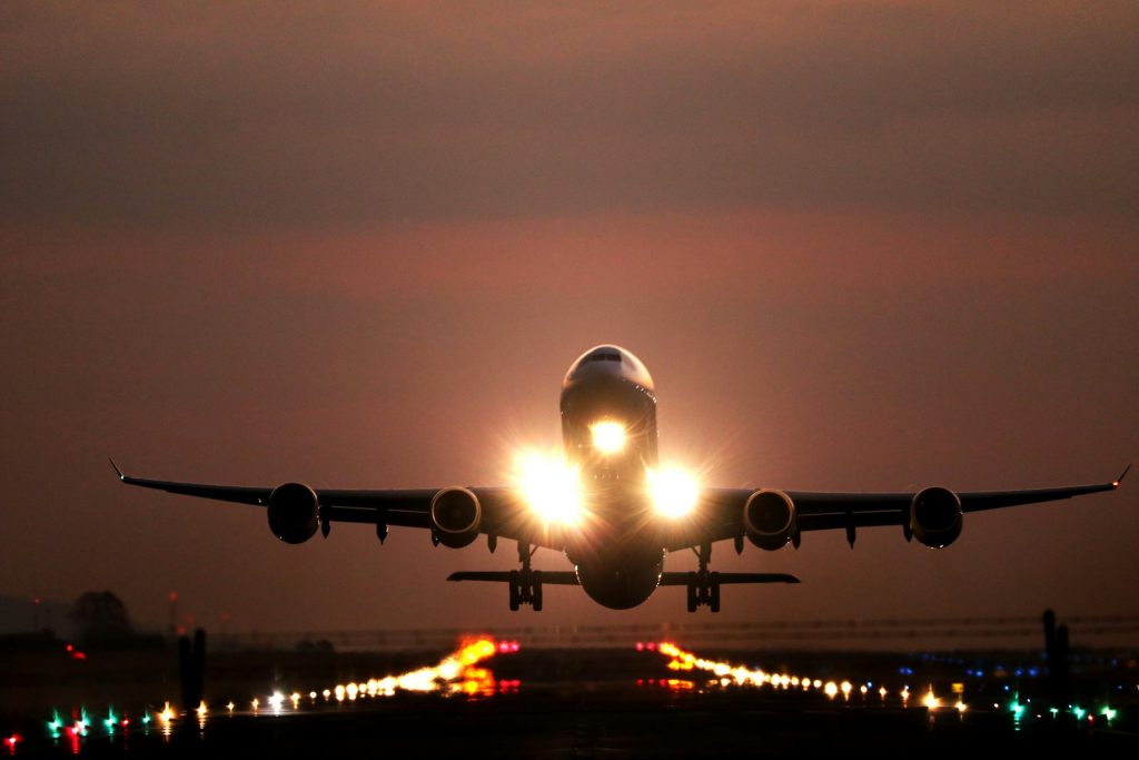 A passenger jet seen from head-on at dusk, low to the runway, about to land or just taking off.