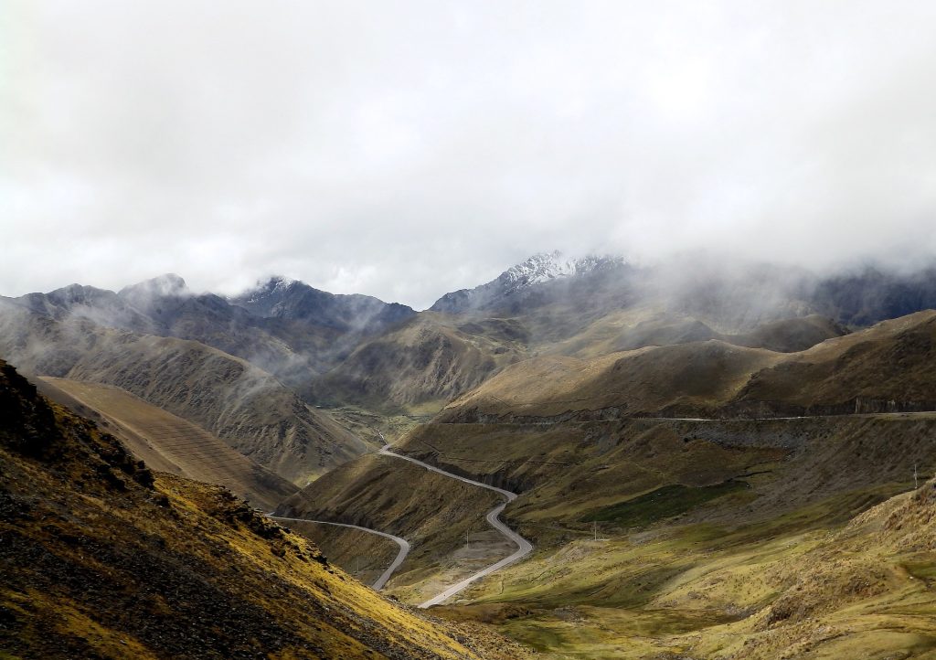 A green valley during daytime, it's peaks slightly obscured by low cloud.