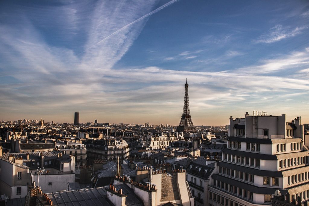 Panoramic view of Paris cityscape with the Eiffel Tower in the distance, surrounded by historic buildings.