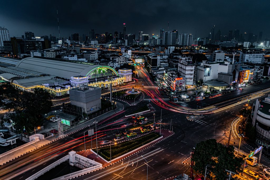 Nighttime cityscape with bustling traffic, light trails from cars, and illuminated buildings, showcasing urban motion.