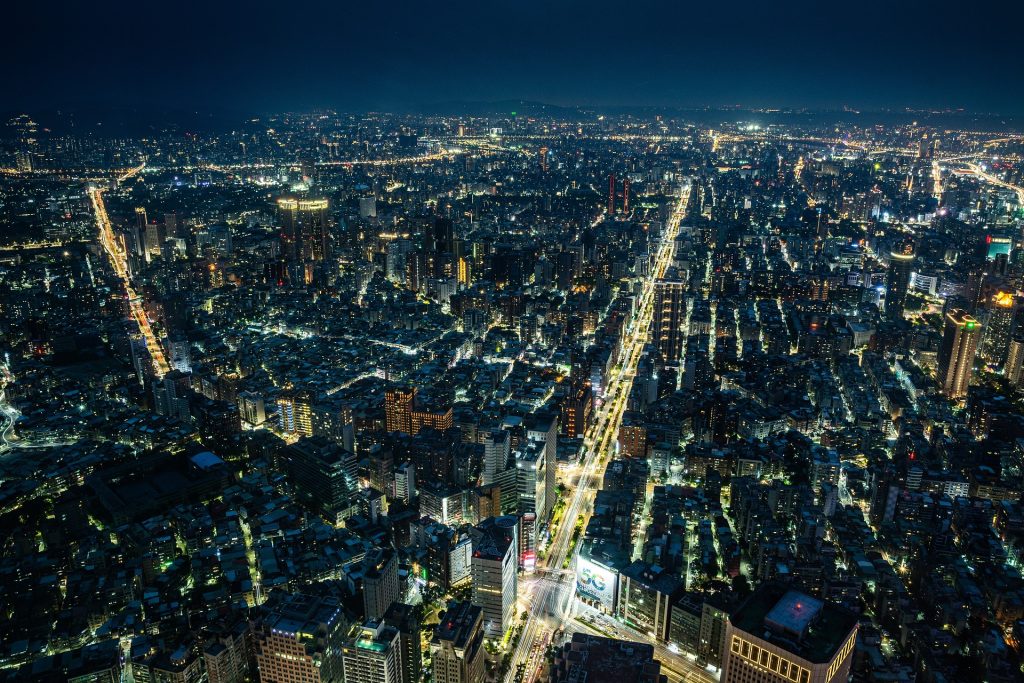 Aerial view of a sprawling city at night with brightly lit streets and buildings, showcasing the vast urban landscape.